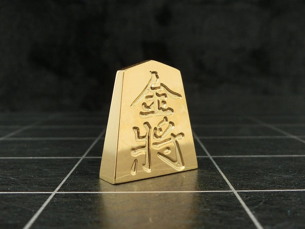 極み 削ることの極 磨き上げる極 一つひとつ職人による手作りでお届けします 24金が美しい将棋駒 実寸大のサイズで作られた、スチールに24金メッキ加工を 施した将棋駒です。精密加工機により実現された精巧な仕上がりで 手作業にて丁寧にっ磨き上げられるからこそ輝く光沢と 滑らかな手触りです。縁起物、インテリア、贈り物、景品としても ご利用いただけます。 駒の大きさは一般的なものと同じですが、 王将の大きさですと35gの重さがあります。 金属ならではの重厚感をお楽しみいただけます。 洗練されたデザインの化粧箱付きです。 購入後、そのままプレゼントしていただけます。 愛好家の方や、ちょっと変わったものが好きな方へのギフトとして おすすめです。大会の景品としても人気です。 高級感のあるインテリアとしてお楽しみいただけます。 # 藤井聡太 さん # 藤井聡太竜王名人 # 藤井聡太八冠