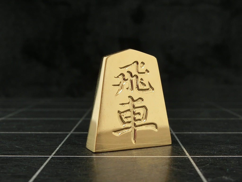 極み 削ることの極 磨き上げる極 一つひとつ職人による手作りでお届けします 24金が美しい将棋駒 実寸大のサイズで作られた、スチールに24金メッキ加工を 施した将棋駒です。精密加工機により実現された精巧な仕上がりで 手作業にて丁寧にっ磨き上げられるからこそ輝く光沢と 滑らかな手触りです。縁起物、インテリア、贈り物、景品としても ご利用いただけます。 駒の大きさは一般的なものと同じですが、 王将の大きさですと35gの重さがあります。 金属ならではの重厚感をお楽しみいただけます。 洗練されたデザインの化粧箱付きです。 購入後、そのままプレゼントしていただけます。 愛好家の方や、ちょっと変わったものが好きな方へのギフトとして おすすめです。大会の景品としても人気です。 高級感のあるインテリアとしてお楽しみいただけます。 # 藤井聡太 さん # 藤井聡太竜王名人 # 藤井聡太八冠