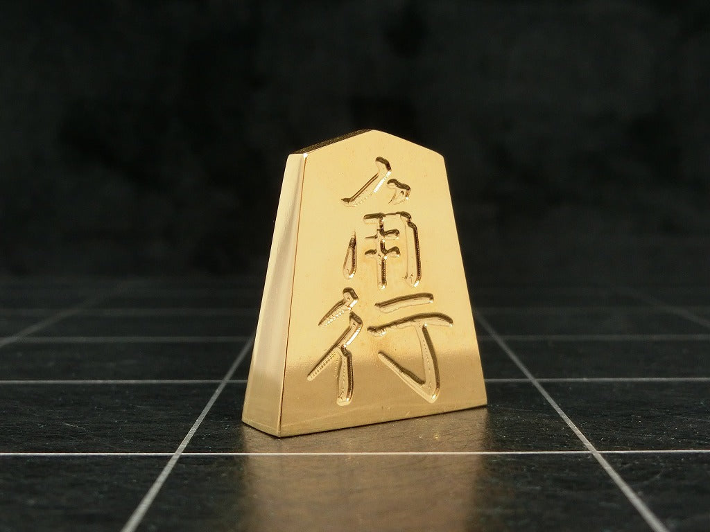 極み 削ることの極 磨き上げる極 一つひとつ職人による手作りでお届けします 24金が美しい将棋駒 実寸大のサイズで作られた、スチールに24金メッキ加工を 施した将棋駒です。精密加工機により実現された精巧な仕上がりで 手作業にて丁寧にっ磨き上げられるからこそ輝く光沢と 滑らかな手触りです。縁起物、インテリア、贈り物、景品としても ご利用いただけます。 駒の大きさは一般的なものと同じですが、 王将の大きさですと35gの重さがあります。 金属ならではの重厚感をお楽しみいただけます。 洗練されたデザインの化粧箱付きです。 購入後、そのままプレゼントしていただけます。 愛好家の方や、ちょっと変わったものが好きな方へのギフトとして おすすめです。大会の景品としても人気です。 高級感のあるインテリアとしてお楽しみいただけます。 # 藤井聡太 さん # 藤井聡太竜王名人 # 藤井聡太八冠